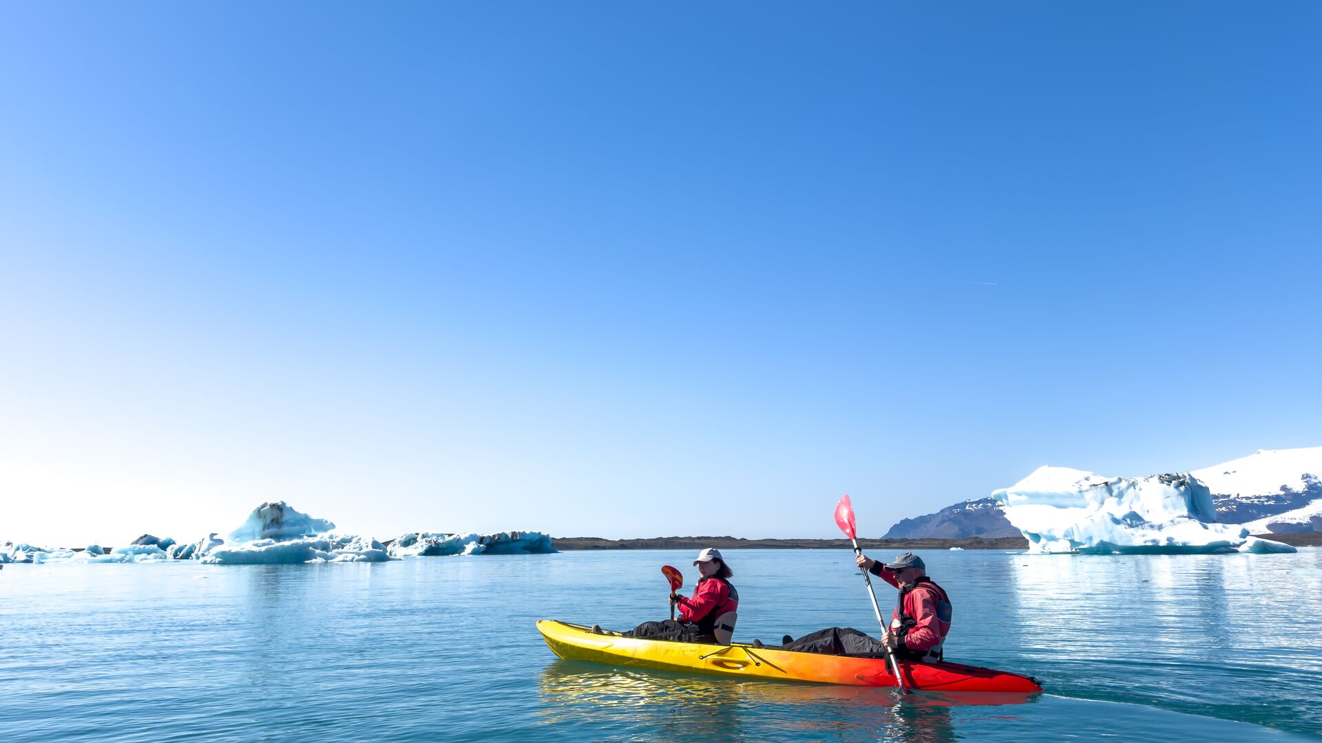 Kayakers paddling around an icy bay in Iceland.