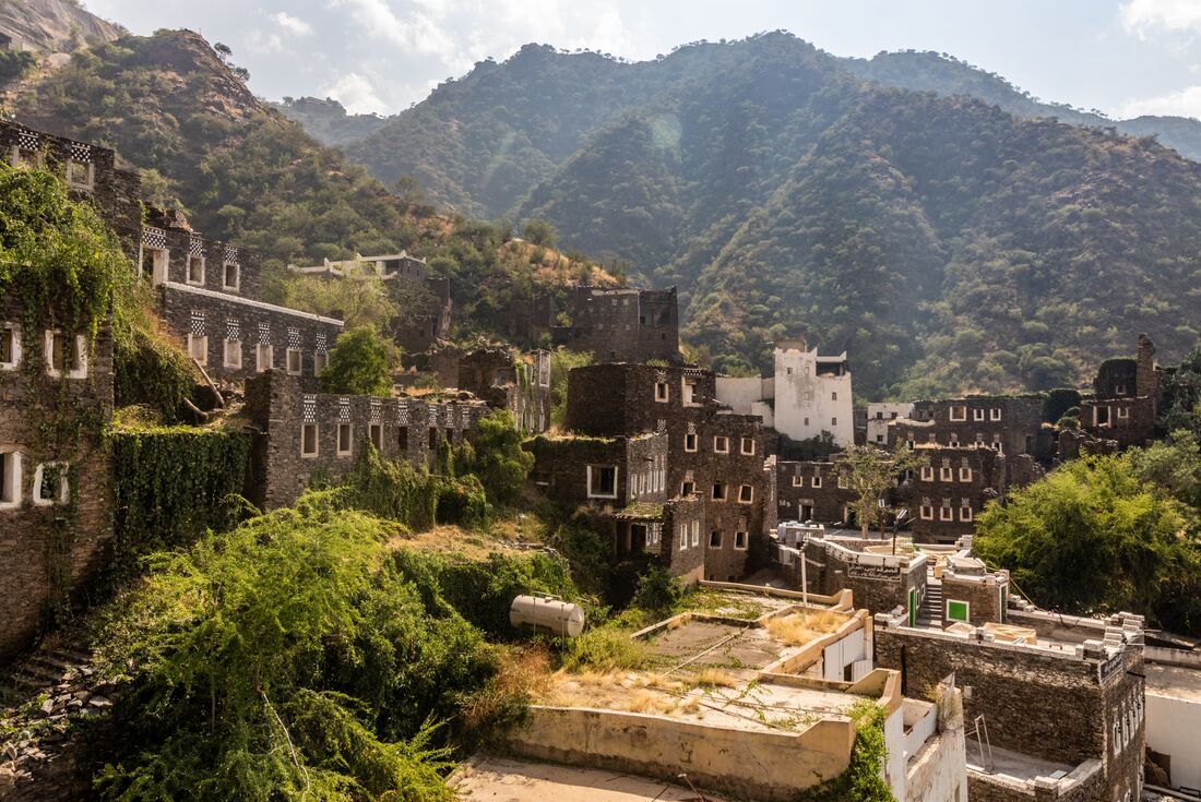 Rijal Almaa village with green vegetation growing on it and mountains in the background, Saudi Arabia