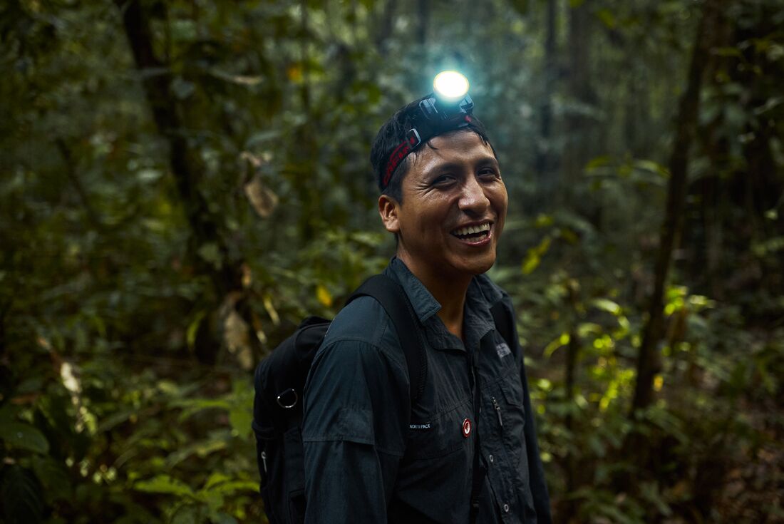 Intrepid leader with headlamp laughs with joy on night walk in the Amazon Peru