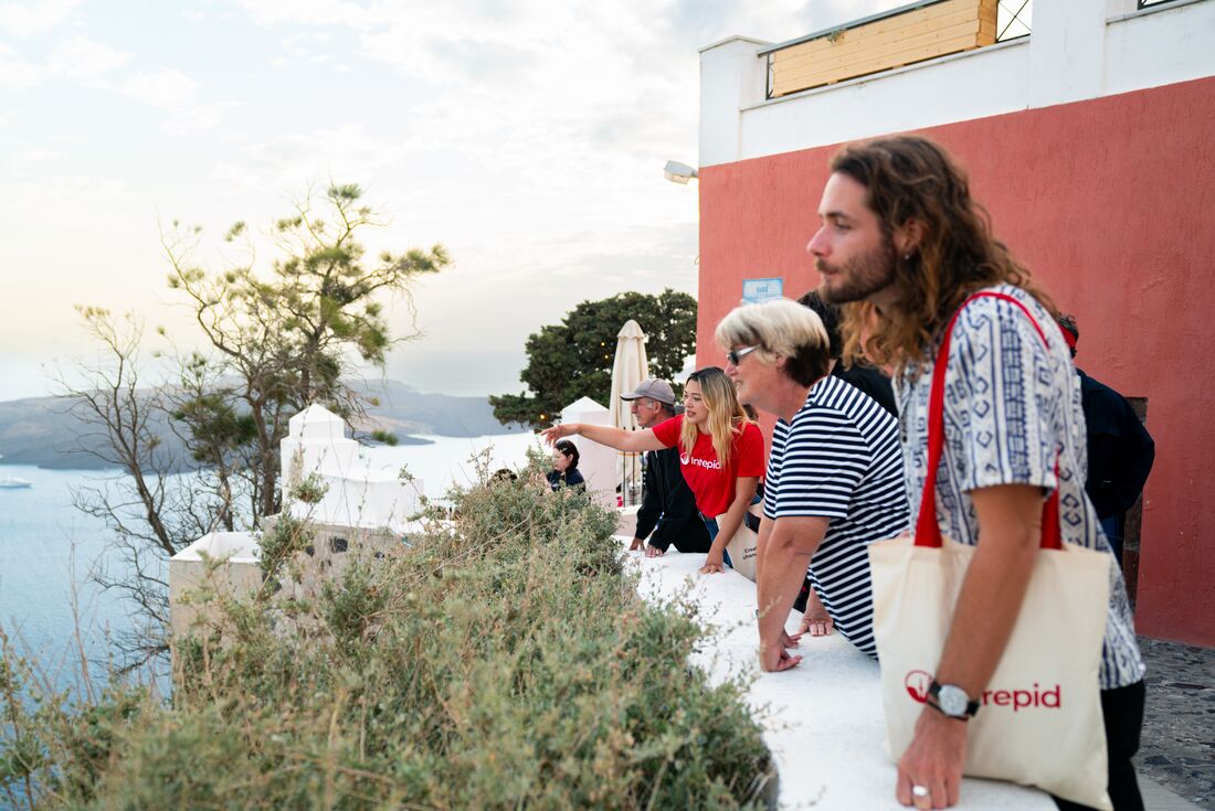 Travellers in Santorini look out from a high balcony on Santorini at the Aegean in Greece