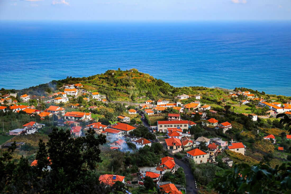 Village of Sao Jorge nestled on high forested cliffs on the island of Madeira with the Atlantic beyond