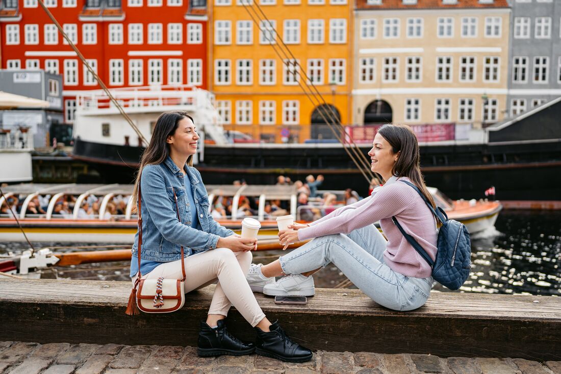 Travellers laugh and enjoy coffee during down time on the Nyhavn Canal in Copenhagen in Denmark