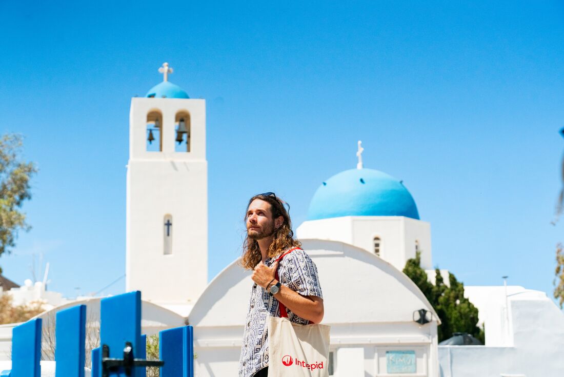 Traveller wandering Santorini, with church dome behind him, Santorini, Greece