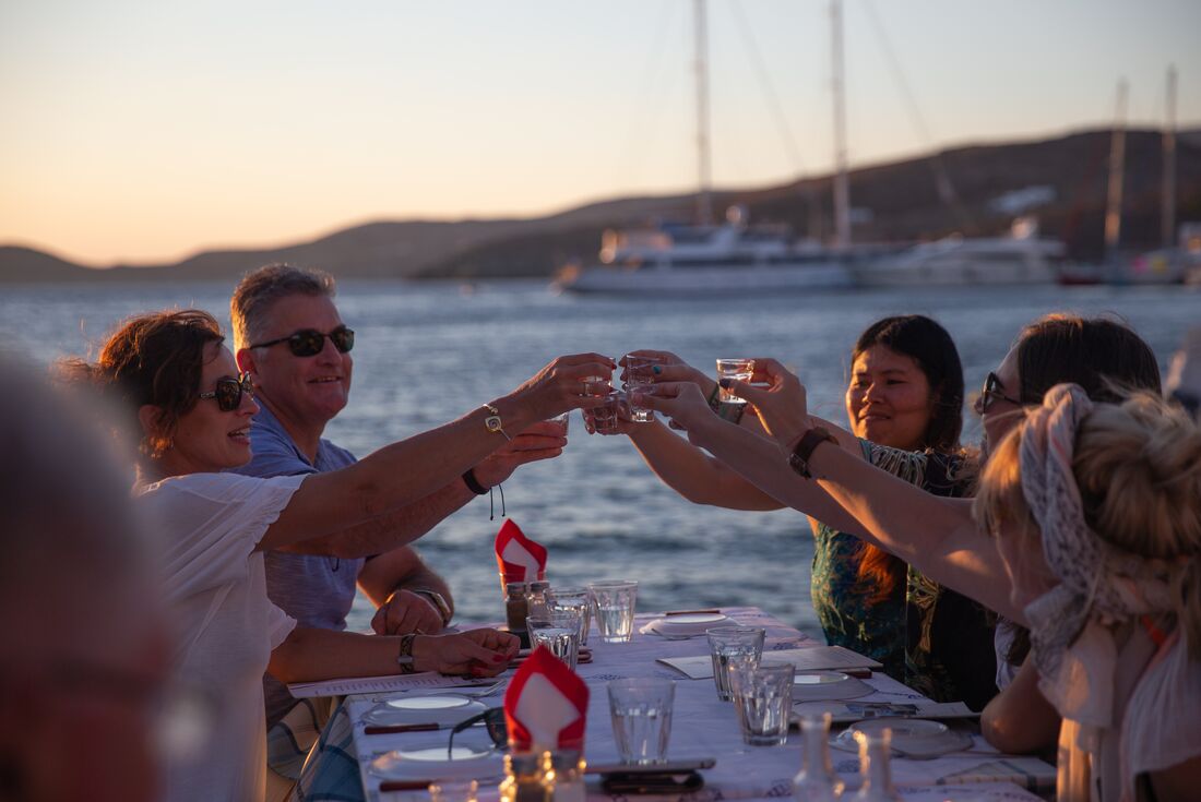 Intrepid travellers share drinks in a waterfront taverna in Kythnos in Greek Cyclades