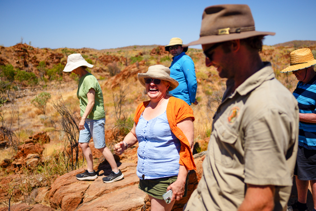 Intrepid travellers of different ages laugha and smile in the orange outback of Western Australia