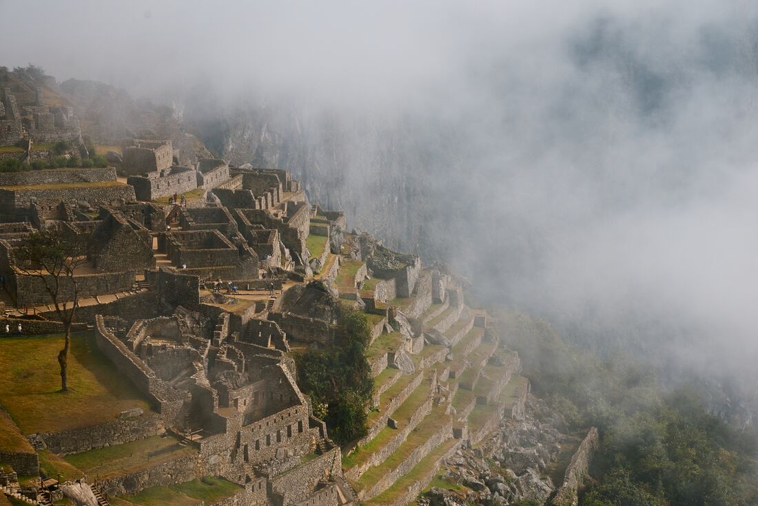 The cut and stepped mountainside architecture of Machu Picchu seen from lookout on a misty morning in Peru
