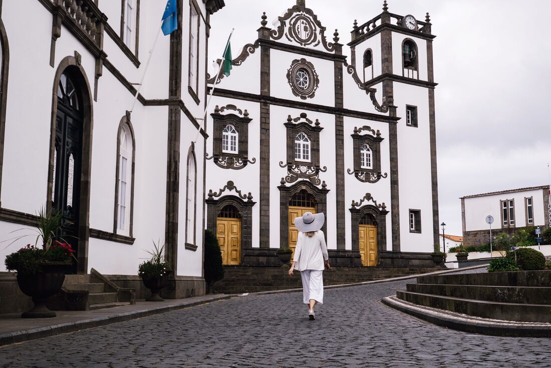 Women wearing a wide brim hat walking the cobble stone streets of Ponta Delgada, Azores, Portugal