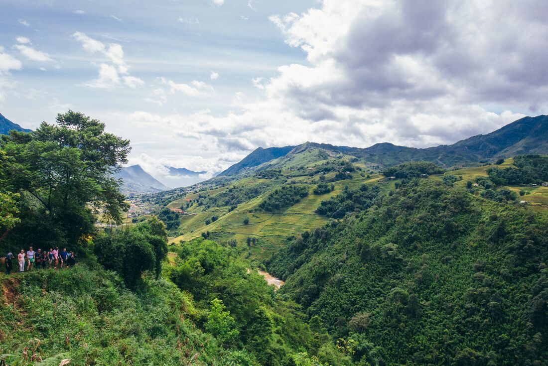 Travellers wave from a hillside on a hike near Sapa Vietnam