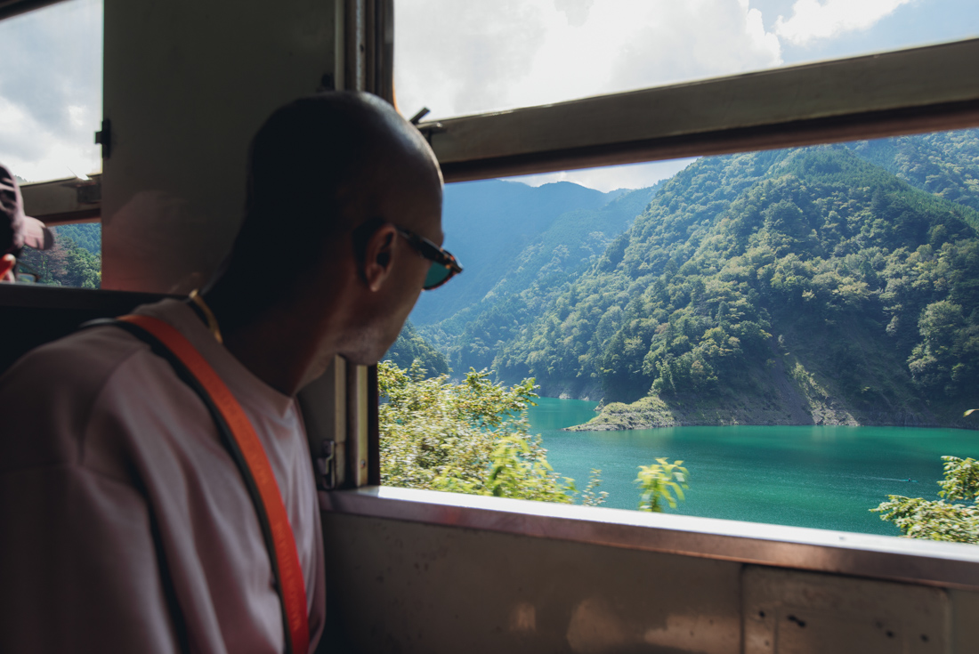 Happy traveller looking out over a river in Japan's mountainous countryside