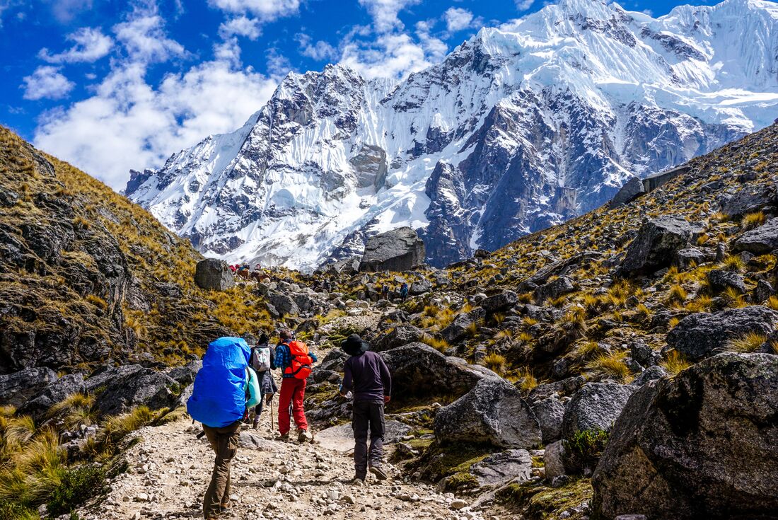 Travellers trekking towards snowcapped mountain Salkantay insight, along the Andes ranges in Peru 