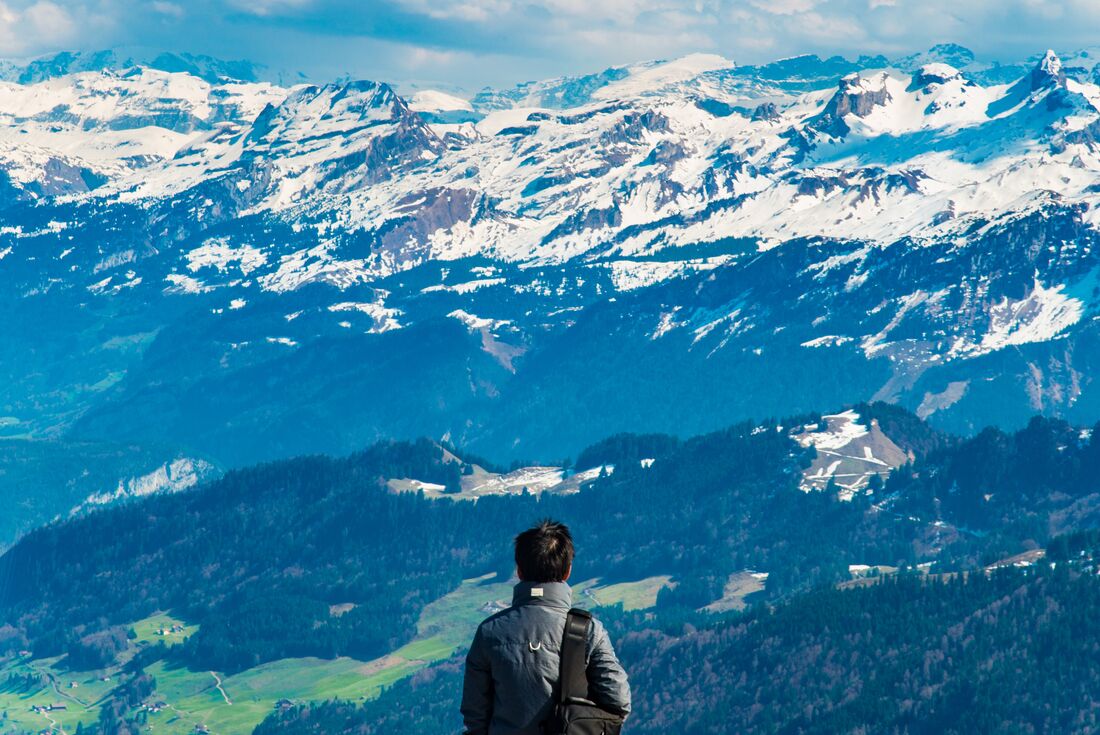 Traveller looks out at snowcapped Swiss Alps from Mount Rigi, near Lucerne, Switzerland