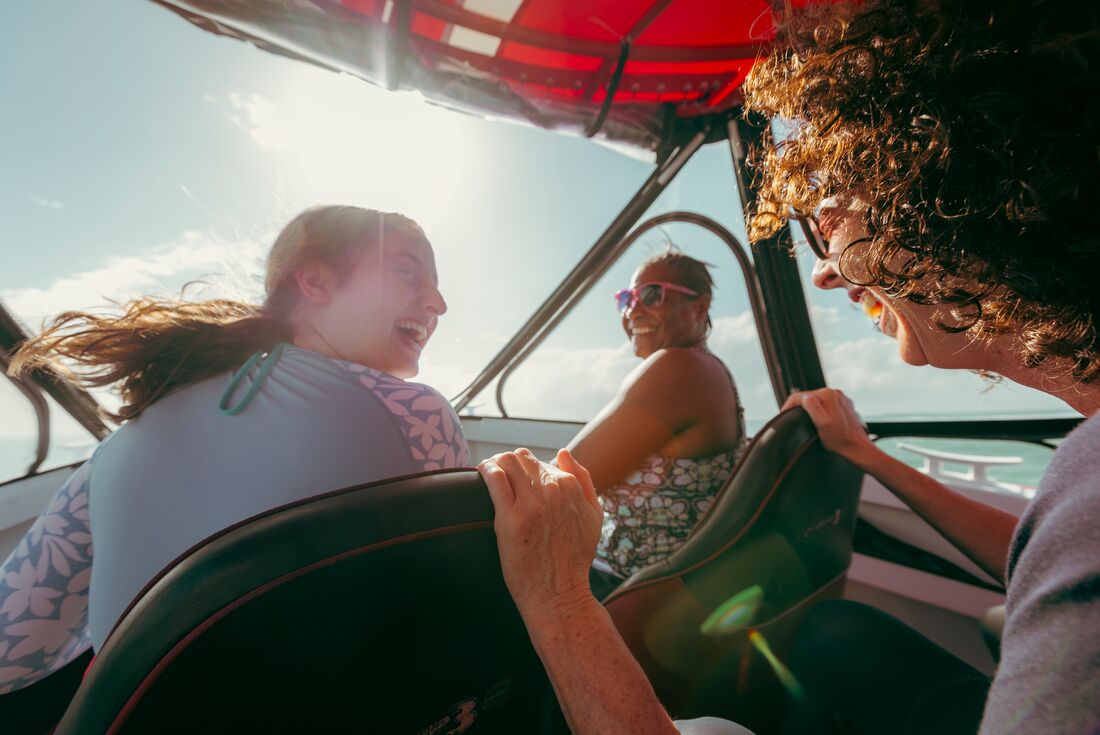 Three travellers laugh together on the boat travelling to snorkel in Port Douglas