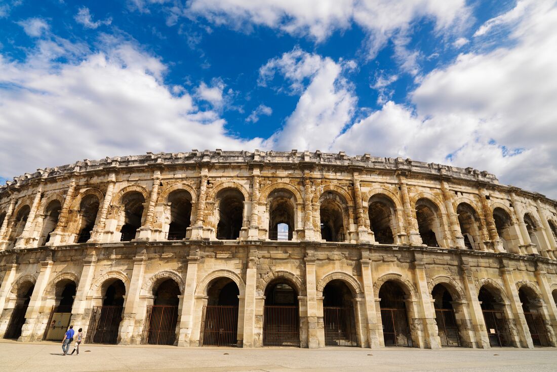 Travellers walk by the Roman ampitheatre Arena of Nimes in Provence France