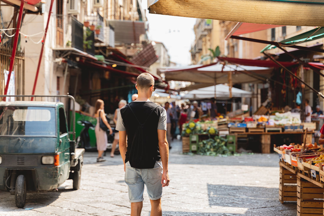 Traveller walking through the street markets of Palermo, Italy