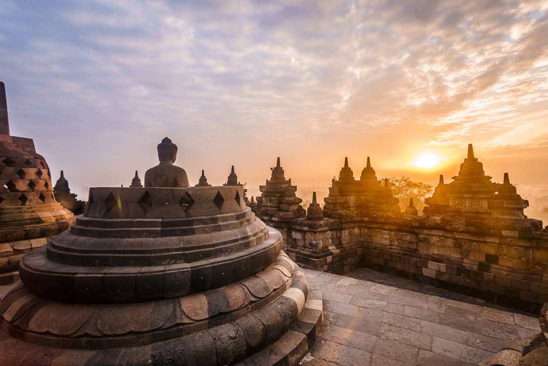An exposed Buddha usually ensconced in a stupa faces the sunrise at Borobudur temple in Indonesia