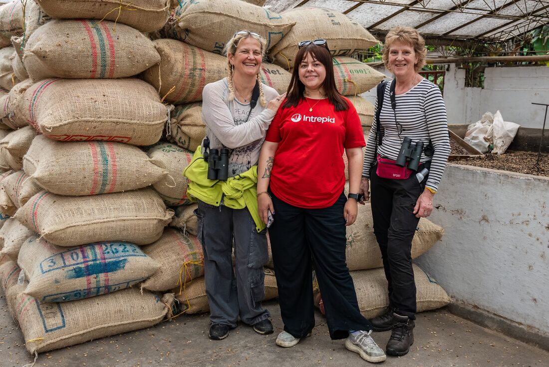 Travellers with guide in front of coffee bags at coffee farm, Chinchina, Colombia